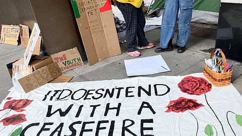 Protesters lay a banner on the sidewalk outside the Fashion Institute of Technology, Friday, April 26, 2024, in New York.