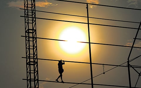 A worker completing hoarding works in the scorching sun at Pallimukku Junction in Kochi on Monday.
