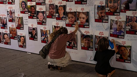 A woman touches photos of Israelis missing and held captive in Gaza, displayed on a wall in Tel Aviv on Oct. 21, 2023.