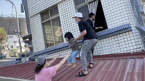 In this image taken from a video footage run by TVBS, residents rescue a child from a partially collapsed building in Hualien, eastern Taiwan on Wednesday, April 3, 2024.