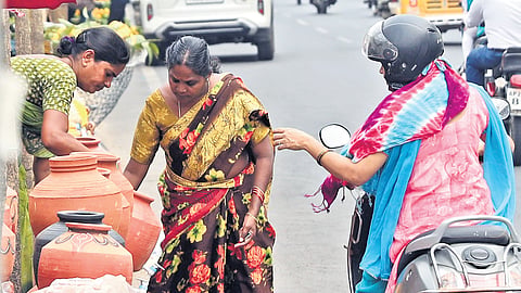 A woman buys earthen water pots from a vendor in Uppal