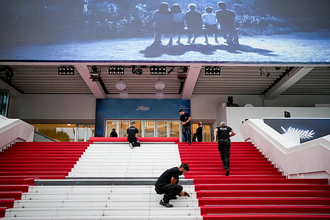 Festival workers lay the red carpet at the Palais des Festivals on opening day of the 77th international film festival, Cannes, southern France, Tuesday, May 14, 2024.