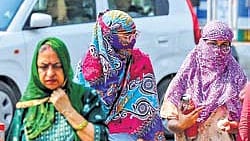 Commuters cover their heads with scarves to shield themselves from the scorching sun on a hot summer day, in Prayagraj on Thursday