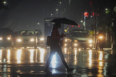 A woman seen crossing the road during the heavy rain near Ashok nagar in Bengaluru.