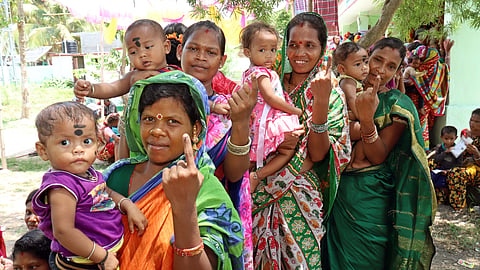 Mothers with the child showing indelible ink fingers marked after casting votes at a polling booth of Luhakote village in Kodala at Odisha.