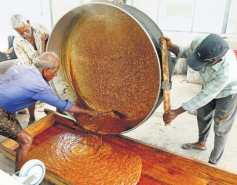 Molten jaggery being poured onto a wooden platform
