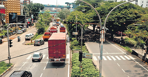 Heavy vehicles moving along the right side of the highway in Kochi