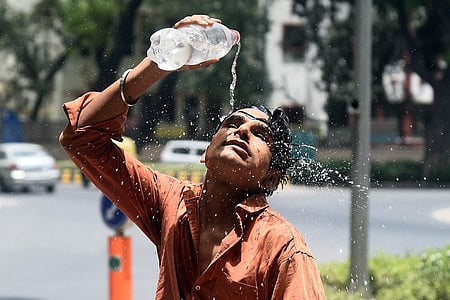A boy sprays water to get some relief from heat wave on a hot summer afternoon in New Delhi On Wednesday, May 29, 2024.