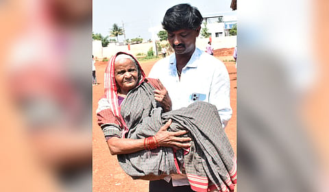 A man carries Lakshmavva, 80, after she cast her vote in Adargunchi village in Dharwad district on Tuesday