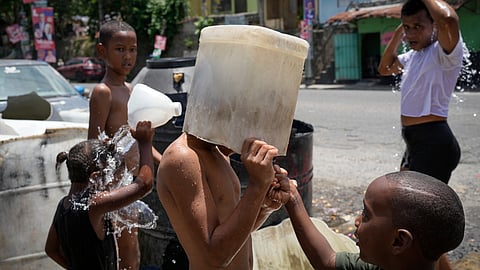A child covers his head with a bucket on a hot day in the Los Guandules neighborhood of Santo Domingo, Dominican Republic