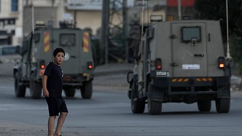 A Palestinian boy watches as Israeli forces' armored vehicles move through the Balata refugee camp in the West Bank city of Nablus, Monday, June 3, 2024.