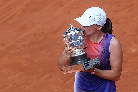 Poland's Iga Swiatek kisses the trophy as she celebrates after winning against Italy's Jasmine Paolini at the end of women's singles final match on Court Philippe-Chatrier on day fourteen of the French Open tennis tournament at the Roland Garros Complex in Paris on June 8, 2024.