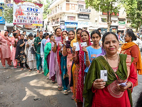 Voters display identity cards while standing in queue to cast their votes at a polling booth during the 7th Phase of General Elections-2024, in Chandigarh, Saturday, June 1, 2024.