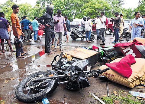 Residents and passers-by near the bike of deceased Jijo Sebastian, 33