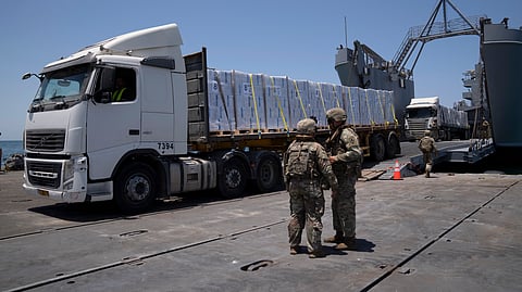 U.S. Army soldiers stand next to trucks arriving loaded with humanitarian aid at the U.S.-built floating pier Trident before reaching the beach on the coast of the Gaza Strip.