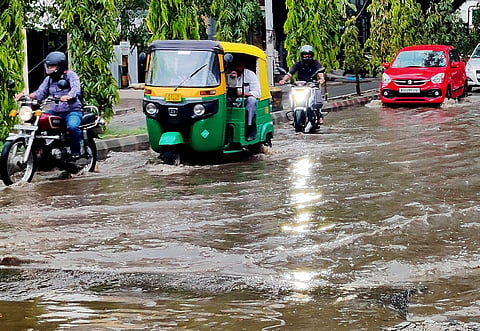 Motorists struggle to navigate an inundated road following heavy rain in Banashankari on Saturday evening