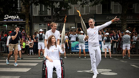 Press agency photographer Christina Assi, left, holds the Olympic torch with. Tinam Pung, right, at the 2024 Summer Olympics, Sunday, July 21, 2024, in Vincennes, outside Paris, France. Assi was struck by a tank shell on Oct. 13, 2023 while reporting clashes between the Israeli army and armed groups in southern Lebanon.
