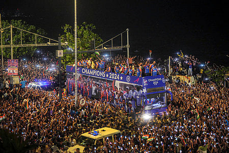 Players of the T20 World Cup-winning Indian cricket team with the championship trophy acknowledge fans during their open bus victory parade