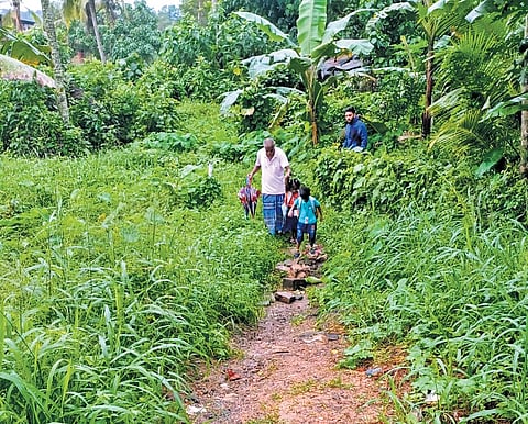An old man seen taking his children through a narrow mudway