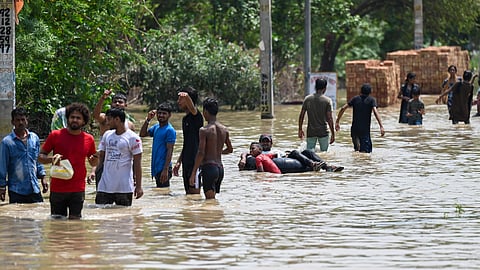 People move to safer places after the barrage of the Munak canal broke and water entered into the residential areas at JJ colony in Bawana in New Delhi on Thursday.