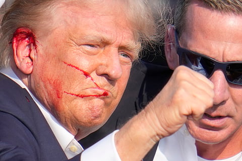 Republican presidential candidate former President Donald Trump gestures while surrounded by U.S. Secret Service agents as he is helped off the stage at a campaign rally in Butler, Pa.