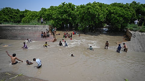 People make their way through a flooded area after a breach in Munak canal that supplies water from Haryana to Delhi, led to knee-deep waterlogging in parts of JJ colony, Bawana, in New Delhi.