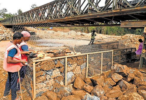 Workers constructing a gabion wall on Wednesday to reinforce the Bailey bridge built by the Army after the massive landslide in Wayanad