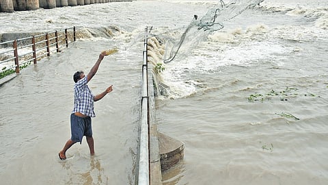 A fisherman casts his net in floodwater at Prakasam Barrage