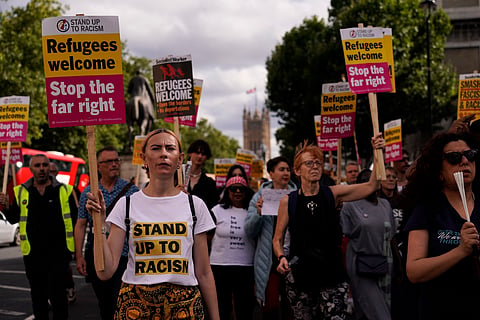 People hold placards as they march during an anti-far right protest in London, Saturday, Aug. 10, 2024.