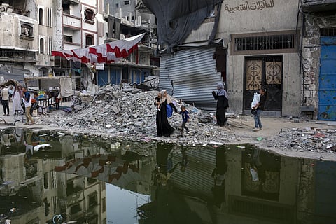 Palestinians displaced by the Israeli air and ground offensive on the Gaza Strip walk next a dark strip of sewage flowing into the streets of the southern town of Khan Younis, Gaza Strip, Thursday, July 4, 2024.