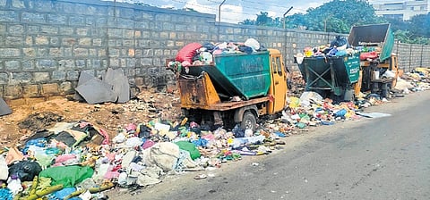 Garbage littered on the road near Kadirenahalli underpass, along with BBMP’s garbage collection mini-autos parked unattended