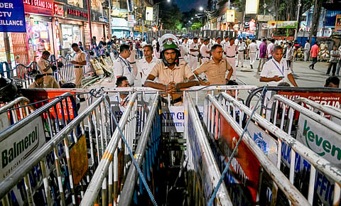 Police personnel stand guard near the barricades set up on a road leading to Lalbazar police headquarters in view of the protest march by junior doctors on Monday
