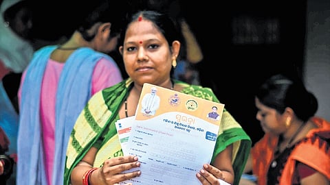 A woman holding a Subhadra Yojana form poses for the camera at a school at Nayapalli in Bhubaneswar on Friday
