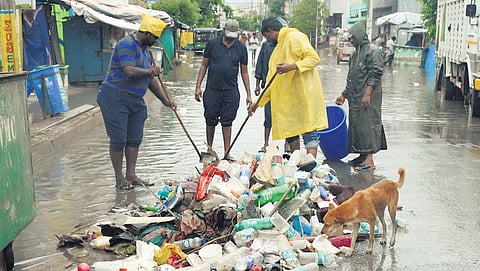 Sanitation workers clearing plastic bottles from the drains.