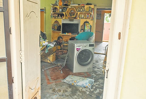 a flood victim near Prakash Nagar cleaning the washing machine as the water recedes on Monday.