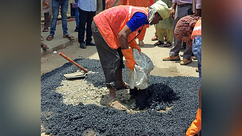 A BBMP worker fills a pothole with tar in Bengaluru.