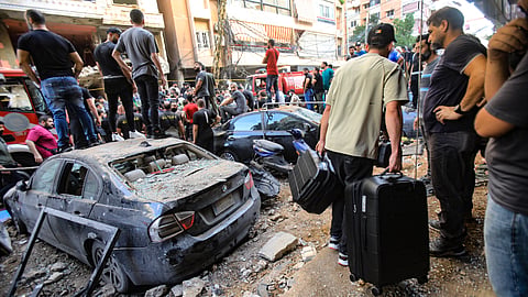 People gather in front of a building targeted by an Israeli strike in Beirut's southern suburbs on September 20, 2024