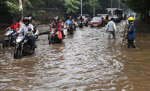 GHMC Workers are seen trying to clear the waterlogged road at VST Junction due to heavy rain on Tuesday in Hyderabad
