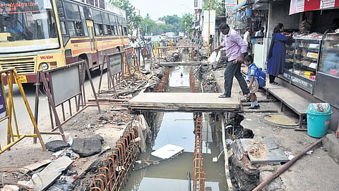 Pedestrians use a makeshift bridge to cross a stormwater drain under construction at Chindadripet on Thursday