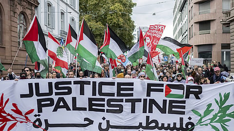 Protesters hold placards and Palestinian flags during a rally in support of the Palestinian people, in Basel, Switzerland, Saturday, Oct. 5, 2024.