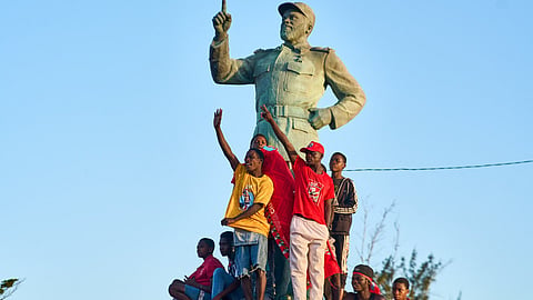 Supporters of Mozambique Liberation Front (FRELIMO) party climb on a statue of former President of Mozambique Samora Machel attend a rally on in Beira on October 6, 2024.
