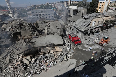 Hezbollah rescue workers use a bulldozer to remove the rubble of destroyed buildings on a commercial street that was hit Saturday night by Israeli airstrikes, in Nabatiyeh town, south Lebanon, Sunday, Oct. 13, 2024.