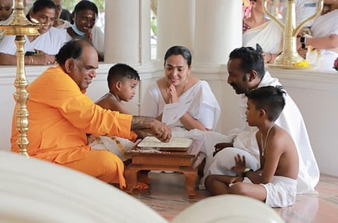 Santhigiri Ashram general secretary Swami Gururatnam Jnana Thapasvi initiates a child into the world of letters during the Vidyarambham ceremony at the Ashram on Sunday.