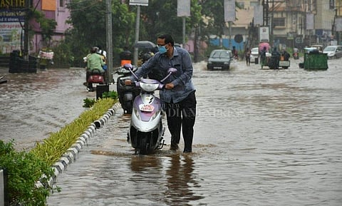 A man walking with a two wheeler on a flooded road in Vijayawada after heavy rains lash Andhra Pradesh.