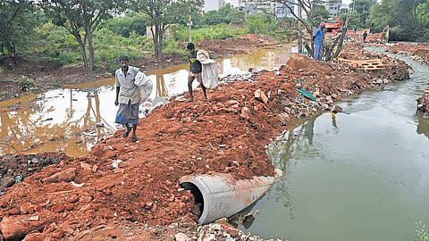 Residents walk on a damaged road between Jakkur and Thanisandra in Dr Shivaram Karanth Layout Phase 2, following heavy rain in Bengaluru