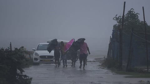 People brave through gusting wind as they walk near Dhamara fishing harbour ahead of cyclone Dana's landfall in Bhadrak district in Odisha on Thursday.
