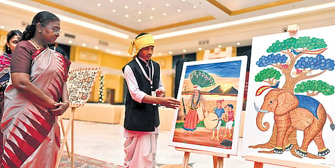 Madavi Anand Rao, a tribal artiste from Adilabad shows his paintings to President Droupadi Murmu at Rastrapati Bhavan in New Delhi