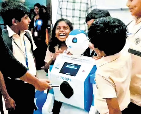 Students surround humanoid robot Poopy after it was introduced at the
Govt UP School, Virakupurakotta