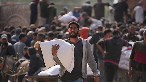 Palestinians gather to receive bags of flour distributed by UNRWA, the U.N. agency helping Palestinian refugees, in Deir al Balah, central Gaza Strip, Saturday, Nov. 2, 2024.
