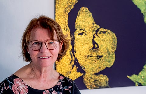 Claudia Huth poses next to a painting showing herself and painted by her son in her house in Egelsbach
